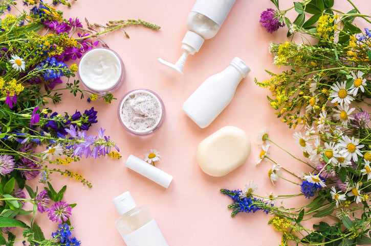 Skincare products arranged with colorful flowers and botanicals